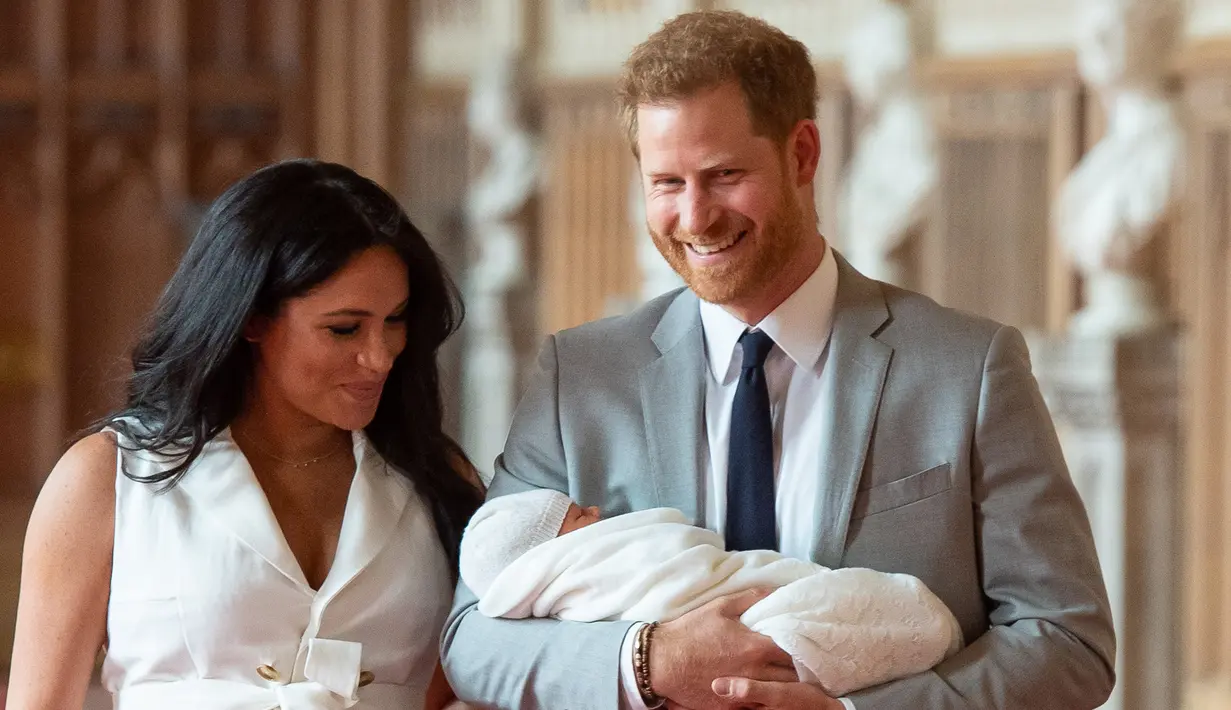 Pangeran Harry dan Meghan Markle berjalan membawa bayi laki-lakinya yang baru lahir di St George's Hall di Windsor Castle di Windsor, London (8/5/2019). Pangeran Harry menyatakan bahwa dia dan Meghan Markle masih memikirkan nama anak mereka. (AFP Photo/Dominic Lipinski)