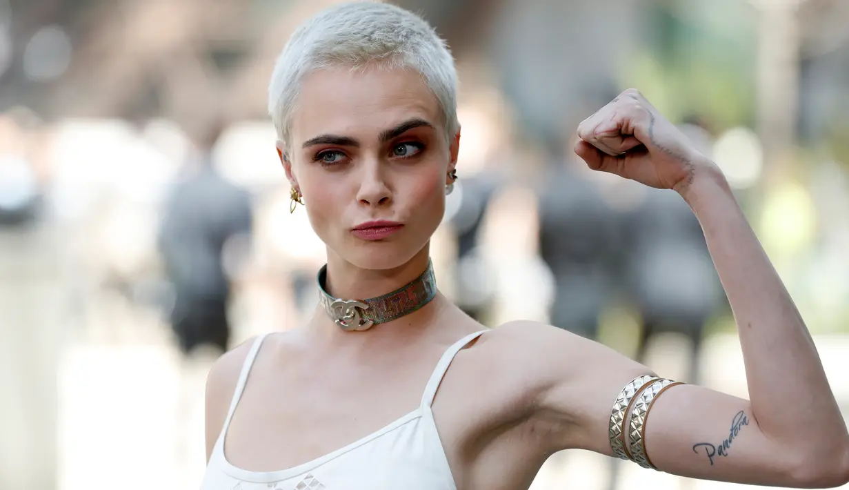 Model Cara Delevingne berpose menunjukkan otot tangannya saat tiba di peragaan busana Chanel Haute Couture di Paris, Prancis, (4/7). Acara ini merupakan bagian dari Paris Fashion Week. (AFP Photo/ Patrick Kovarik)