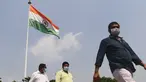 Sejumlah pria mengenakan masker berjalan melewati bendera nasional India di New Delhi (16/9/2020). Total kasus Covid-19 di India melampaui lima juta pada 16 September, data kementerian kesehatan menunjukkan Pandemi meluas cengkeramannya di negara tersebut. (AFP/Sajjad Hussan)