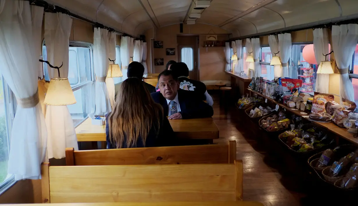 Sejumlah orang mengunjungi gerbong kereta tua yang diubah menjadi kafe di La Paz, Bolivia pada 15 Maret 2019. Selain dimanfaatkan sebagai kafe, bagian gerbong kereta juga dijadikan toko yang menjual produk makanan dan minuman. (David Mercado/Reuters)