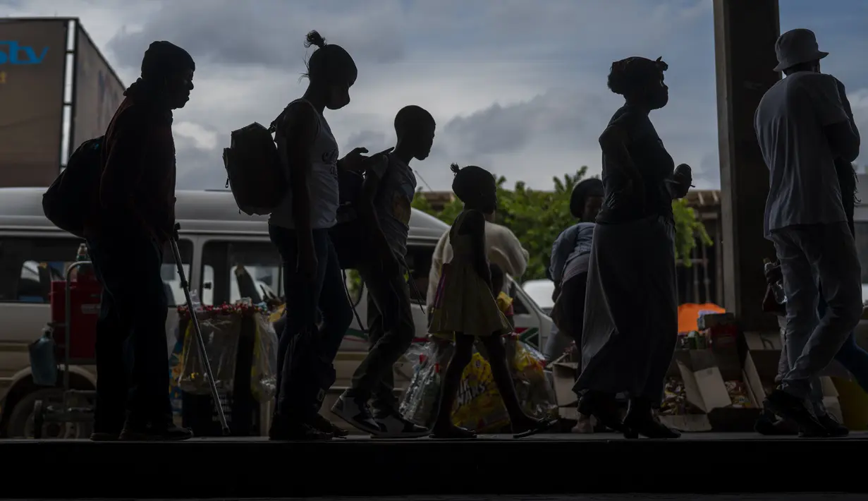 Penumpang, beberapa mengenakan masker, antre untuk naik taksi di pangkalan taksi Baragwanath di Soweto, Afrika Selatan, Kamis (2/12/2021). Afrika Selatan mempercepat kampanye vaksinasi untuk memerangi lonjakan pesat kasus Covid-19 usai mendeteksi varian Omicron pekan lalu. (AP Photo/Jerome Delay)