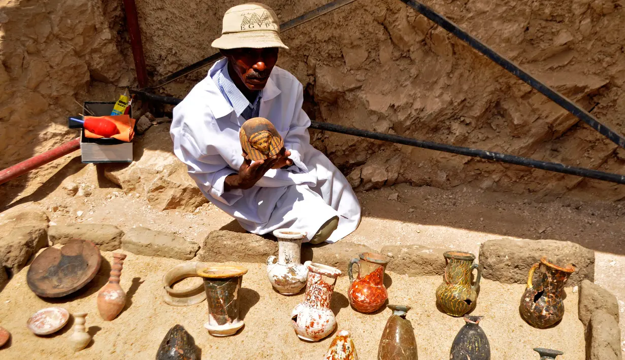 Seorang arkeolog Mesir memperlihatkan sejumlah artefak yang ditemukan di sebuah pemakaman berumur 3.500 tahun, sebelah selatan kota Luxor, Selasa (18/4). Kuburan yang ditemukan di Draa Abul Nagaa itu diperkirakan berasal dari Dinasti ke-18. (STRINGER/AFP)