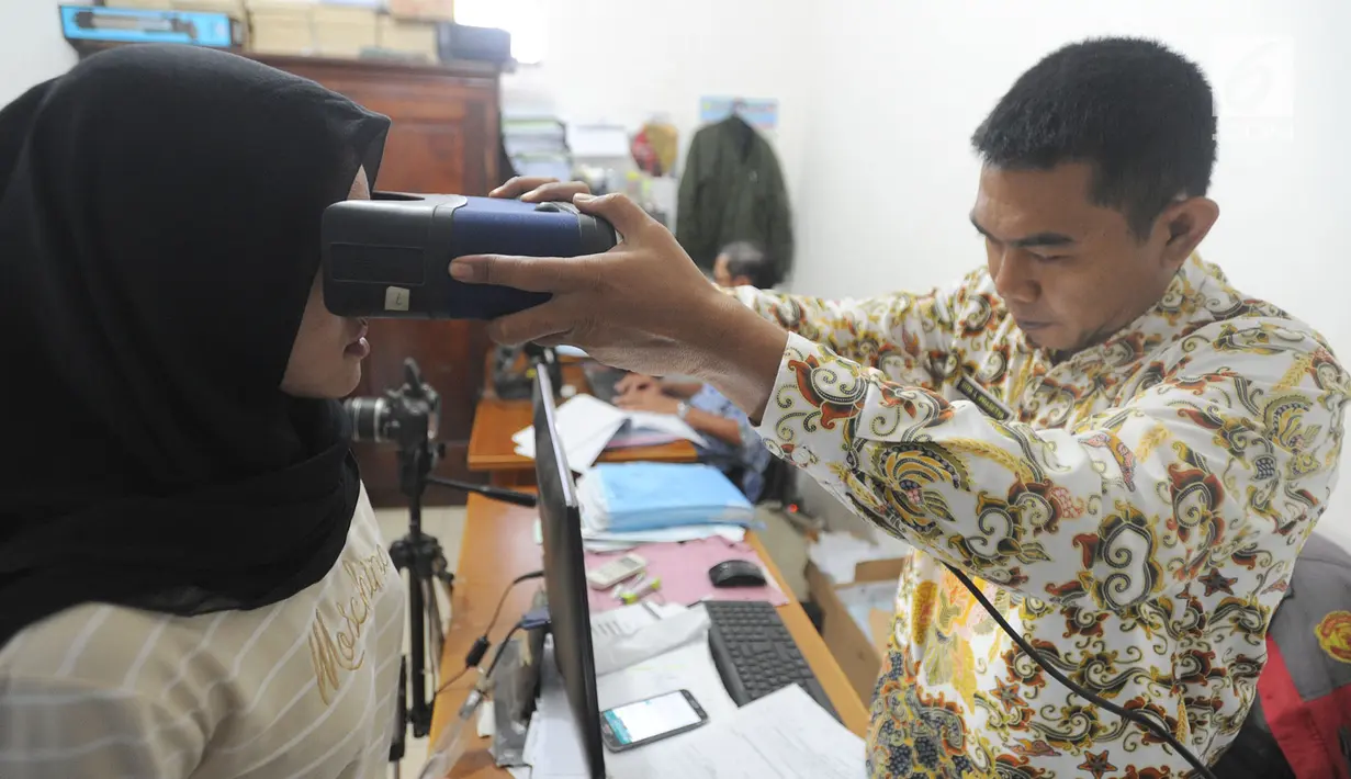 Petugas memindai retina seorang warga saat pembuatan E-KTP di Kantor kelurahan Cinere, Depok, Kamis (27/12). Hari ini Disdukcapil daerah melaksanakan pelayanan jemput bola perekaman E-KTP serentak khusus pemula secara nasional. (Merdeka.com/Arie Basuki)