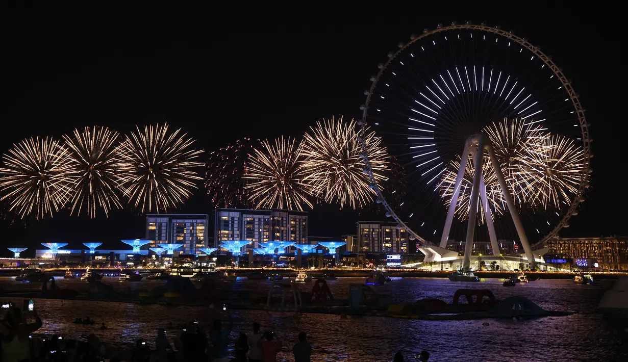 Kembang api menerangi langit selama upacara pembukaan Dubai Eye, yang dikenal sebagai Ain Dubai, di kota Emirat, dekat Dubai Marina, Kamis (21/10/2021). Dubai Eye memiliki tinggi 250 meter dan mampu menampung 1750 pengunjung dalam satu kali rotasi yang berlangsung 30 menit. (Giuseppe CACACE / AFP)