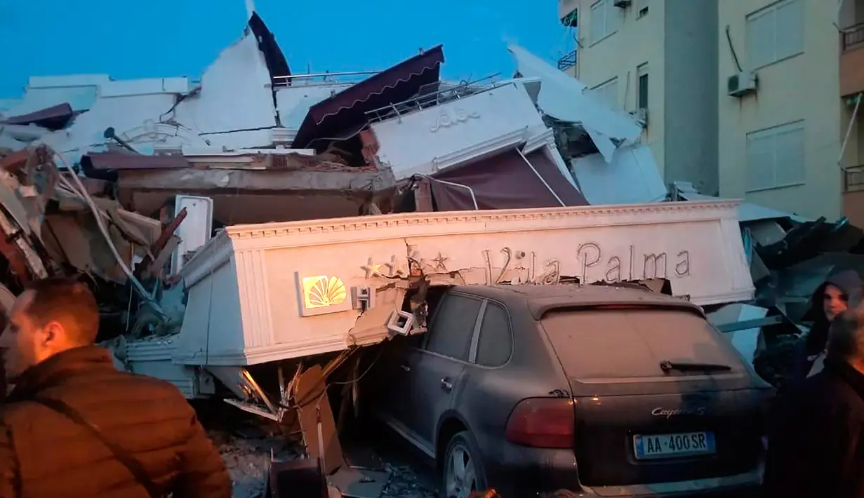 Sebuah mobil tetrimpa puing bangunan hotel yang rusak setelah gempa bumi di Durres,  Albania barat, Selasa (26/11/2019). Gempa bumi bermagnitudo 6,4 mengguncang Albania, Selasa dini hari yang menyebabkan beberapa bangunan dan gedung permukiman runtuh. (AP Photo)