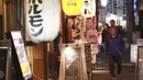 Orang-orang melintasi jalan di Tokyo, Jepang, Senin (25/10/2021). Orang-orang di Tokyo dapat makan dan minum di bar dan restoran mulai Senin malam ketika aturan jarak sosial dilonggarkan karena kasus COVID-19 harian di negara itu mencapai level terendah dalam setahun lebih. (AP Photo/Koji Sasahara)
