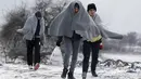 Sejumlah imigran berjalan dengan menutupi tubuhnya dengan kain setelah melintasi hamparan salju dari perbatasan Macedonia di dekat desa Miratovac, Serbia, (18/1/2016). (REUTERS/Marko Djurica)