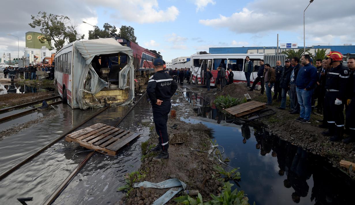 Sejumlah orang berkumpul di lokasi kecelakaan antara kereta dengan sebuah bus di rel dekat wilayah Sidi Fathallah, sekitar 10 km selatan Ibu Kota Tunisia, Rabu (28/12). Penyelidikan tengah dilakukan untuk mencari tahu apa yang terjadi. (Fethi Belaid/AFP)