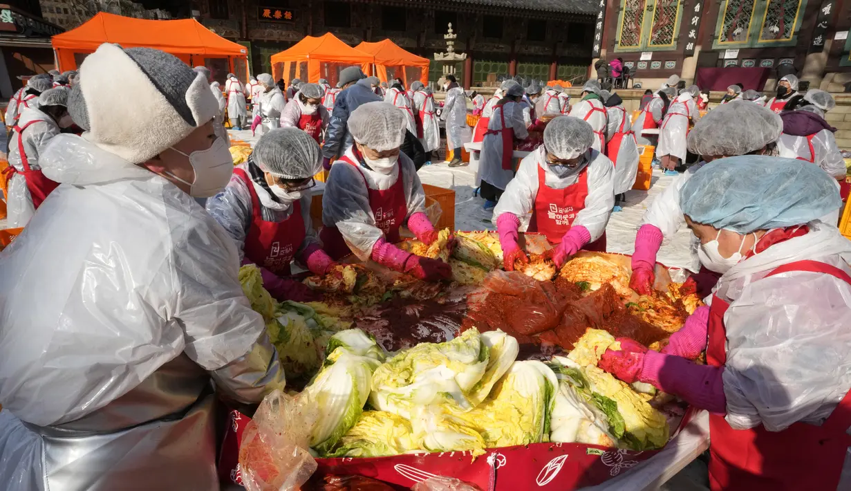 Relawan mencampurkan bahan-bahan saat membuat kimchi untuk disumbangkan kepada tetangga yang membutuhkan, di sebuah kuil di Seoul, Korea Selatan, Kamis (2/12/2021). Sekitar 200 orang membuat 4.000 bungkus kimchi, makanan tradisional paling populer di Korea. (AP Photo/Ahn Young-joon)