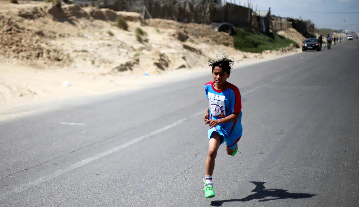 Seorang anak Palestina bersemangat berlari selama maraton lokal yang diselenggarakan oleh Culture and Free Thought association di Khan Younis di Jalur Gaza selatan (28/4/2016). (REUTERS / Ibraheem Abu Mustafa)
