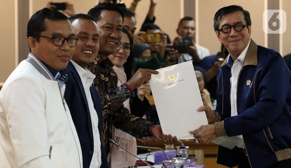 Menkumham Yasonna Laoly menyerahkan berkas kepada Ketua Baleg DPR Supratman Andi Agtas dalam rapat kerja di Kompleks Parlemen, Senayan, Kamis (16/1/2020). Baleg DPR membuka peluang mengurangi jumlah RUU program legislasi nasional (prolegnas) prioritas tahun 2020-2021. (Liputan6.com/Johan Tallo)