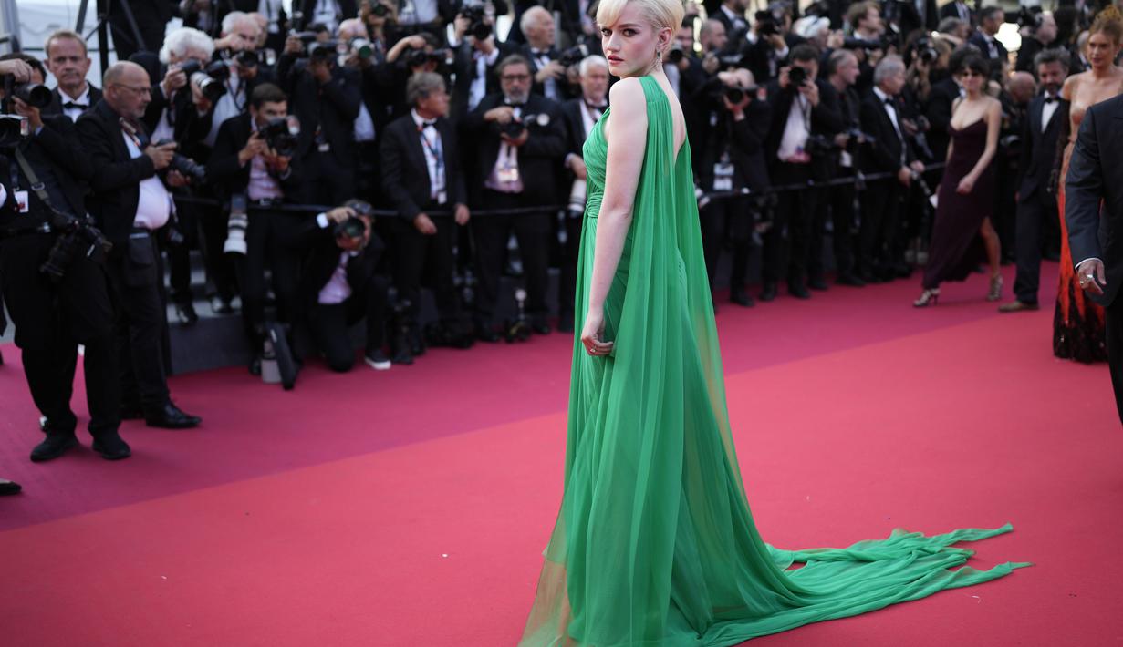 <p>Julia Garner memadukan gaun yang mencuri perhatian dengan anting-anting lampu gantung berlian dan platform perak Gucci Angel. (Photo by Scott Garfitt/Invision/AP)</p>