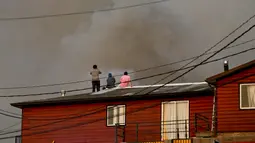 Sejumlah warga melihat kepulan asap di atas rumah mereka di kawasan Dichato Chili, Senin (30/1). Kekeringan, angin kencang dan suhu tinggi telah memicu serangkaian kebakaran di Central Chile sejak November 2016. (AP Photo / Esteban Felix)