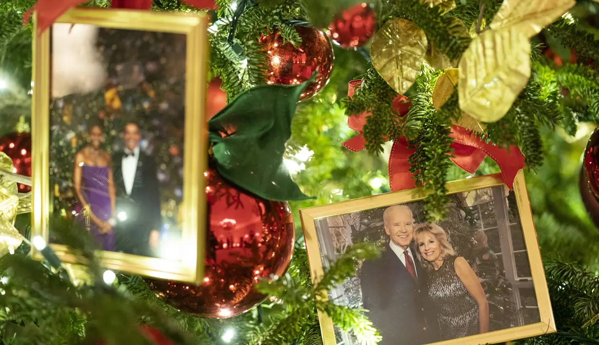 Foto Presiden AS Joe Biden dan ibu negara Jill Biden bertengger di pohon Natal di Ruang Makan Negara selama pratinjau pers dekorasi Natal Gedung Putih, di Washington, Senin (29/11/2021). Gedung Putih meluncurkan dekorasi liburan 2021 dengan tema “Gifts from the Heart”. (AP Photo/Evan Vucci)