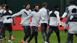 Gelandang Liverpool Mohamed Salah (tengah) bercanda dengan rekan setimnya saat sesi latihan jelang menghadapi Bayern Munchen dalam leg kedua babak 16 besar Liga Champions di Melwood, Liverpool, Inggris, Selasa (12/3). (Paul ELLIS/AFP)