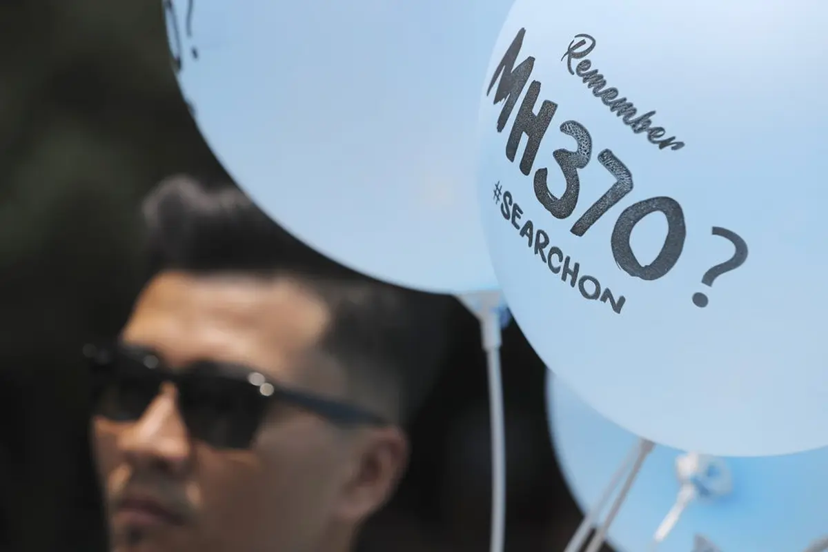 Seorang relawan membagikan balon bergambar MH370 pada acara Day of Remembrance MH370 di Kuala Lumpur, Malaysia, Minggu, 3 Maret 2019. (Foto AP/Vincent Thian)