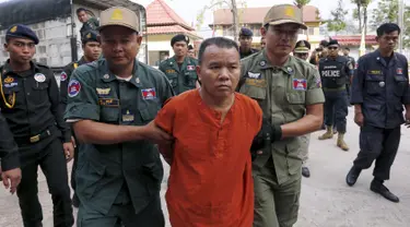 Yem Chrin (tengah) dikawal oleh petugas polisi saat tiba di Pengadilan Provinsi Battambang,Kamboja,Kamis (3/12). Pengadilan Kamboja menghukum Yem Chrin  25 tahun penjara dengan kasus pembunuhan dan penyebaran HIV lebih dari 270 orang. (REUTERS/Stringer)