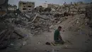 Seorang pria Palestina berdoa di samping puing-puing rumah keluarganya yang hancur karena serangan udara Israel di Beit Lahia, Jalur Gaza, Jumat (4/6/2021). Gencatan senjata yang mengakhiri perang 11 hari antara Hamas dan Israel telah lama dilakukan. (AP Photo/Felipe Dana)