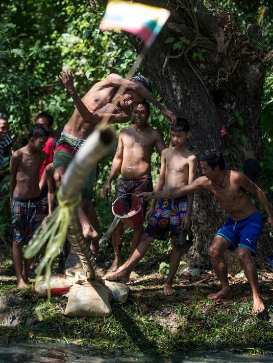 Seorang pria berjalan di atas tiang untuk mencoba meraih bendera nasional memperingati Hari Kemerdekaan Myanmar di pinggiran Yangon (4/1). Myanmar merayakan peringatan ke-71 deklarasi kemerdekaannya dari kolonial Inggris. (AFP Photo/Ye Aung Thu)