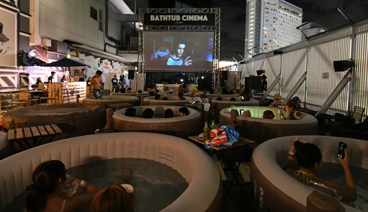 Pengunjung menikmati menonton film sambil berendam di Bathtub Cinema di atap gedung kawasan Shibuya, Tokyo, 17 Agustus 2018. Penyelenggara menyediakan 12 bak mandi bundar yang setiap bathtubnya dapat diisi oleh empat orang. (AFP/Kazuhiro NOGI)