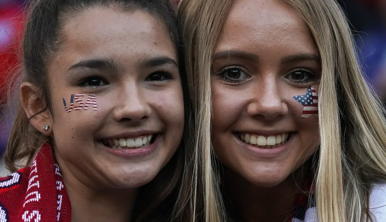 Dua fans wanita AS tersenyum sebelum pertandingan Grup F Piala Dunia Wanita 2019 antara Amerika Serikat melawan Thailand di Stadion Auguste-Delaune di Reims, Prancis (11/6/2019). (AFP Photo/Lionel Bonaventure)