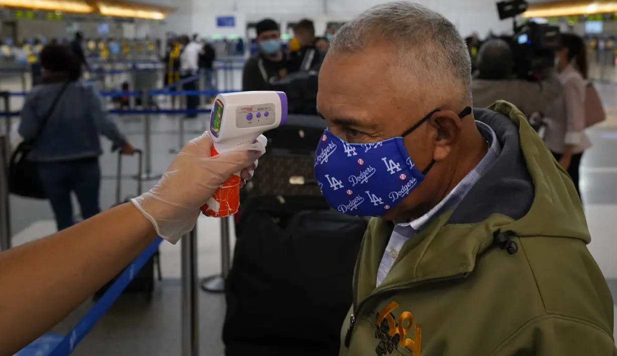Pelancong diperiksa suhu tubuhnya saat mengantri untuk check-in di Bandara Internasional Los Angeles di Los Angeles, California, 23 November 2020. Menjelang Thanksgiving, Pusat Pengendalian Penyakit mengimbau agar orang Amerika tak bepergian di tengah lonjakan Covid-19 di AS. (AP Photo/Jae C. Hong)