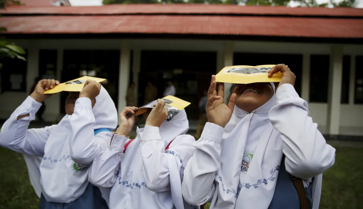 Sejumlah siswi mengunakan kacamata filter melihat matahari saat workshop bersama Hong Kong Astronomical Society dan LAPAN di sekolah di Ternate, (7/3). Kacamata ini akan digunakan untuk mengamati Gerhana Matahari Total. (REUTERS/Beawiharta)