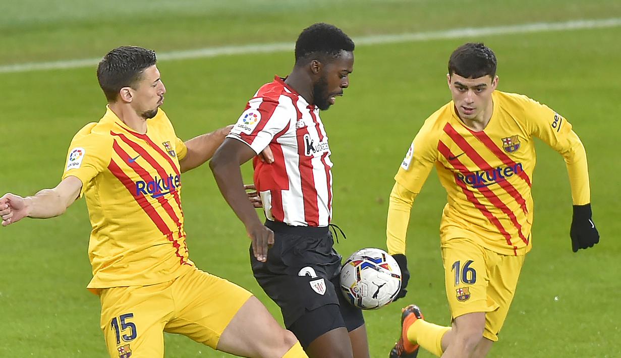 Striker Athletic Bilbao, Inaki Williams (tengah) dikepung dua pemain Barcelona, Clement Lenglet (kiri) dan Pedri dalam laga lanjutan Liga Spanyol 2020/21 di San Mames Stadium, Bilbao, Rabu (6/1/2021). Athletic Bilbao kalah 2-3 dari Barcelona. (AFP/Ander Gillenea)
