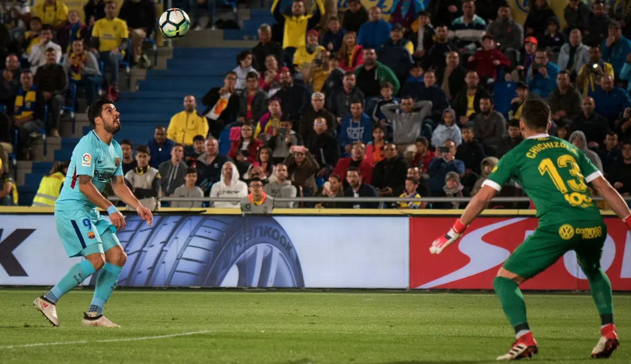 Pemain Barcelona, Luis Suarez melihat bola di depan kiper Las Palmas, Leandro Chichizola pada jornada ke-26 La Liga 2017-2018 di Estadio Gran Canaria, Kamis (1/3). Barcelona hanya memetik hasil imbang 1-1 dari tim papan bawah klasemen (DESIREE MARTIN/AFP)