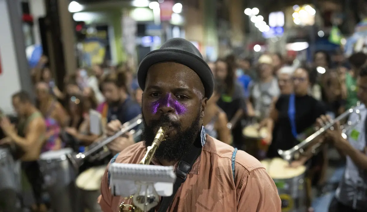 Musisi pesta jalanan yang dikenal sebagai blocos, memainkan musik selama protes terhadap pembatasan oleh pejabat kota di Rio de Janeiro, Brasil (13/4/2022). Balai Kota telah melarang pesta jalanan selama perayaan Karnaval, yang tertunda hampir dua bulan karena pandemi. (AP Photo/Silvia Izquierdo)