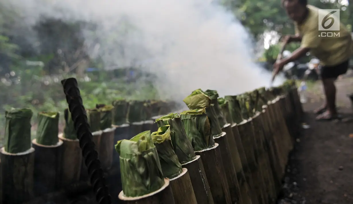 Pak Pian memeriksa kayu bakar saat memasak lemang bambu sebuah tanah kosong di Jakarta, Minggu (27/5). Pak Pian mengaku dapat memproduksi hingga 100 buah lemang per hari di bulan Ramadan. (Merdeka.com/Iqbal S Nugroho)