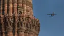Pesawat terbang melintas dekat situs warisan dunia UNESCO Qutub Minar di New Delhi, India, Kamis (13/2/2020). Ayat Alquran yang terukir di bangunan Qutub Minar bersanding dengan karakter hiasan Parso-Arab dan Nagari. (Xinhua/Javed Dar)