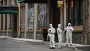 Pekerja yang mengenakan alat pelindung diri dan mengantarkan makanan berdiri di sebelah akses hotel di Bund, Puxi, Shanghai, China, 31 Maret 2022. Daerah Puxi akan lockdown mulai 1 April 2022. (Hector RETAMAL/AFP)