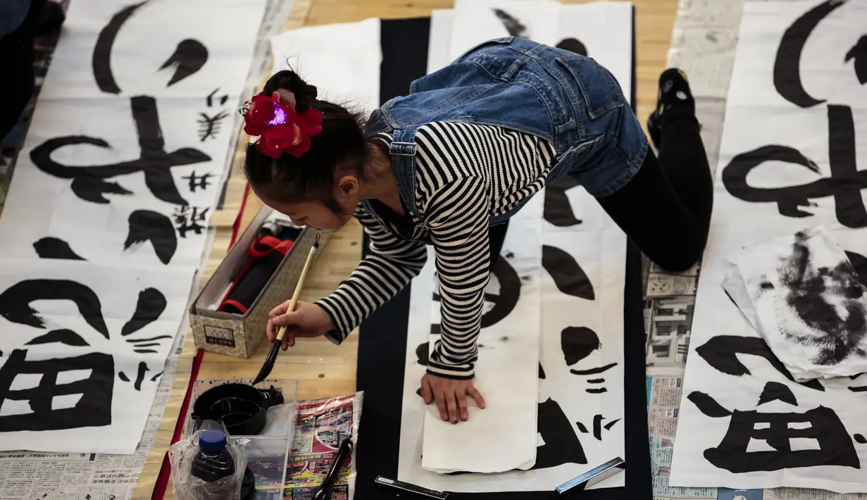 Seorang peserta mencelupkan tinta untuk membuat tulisan Jepang saat mengikuti lomba kaligrafi Tokyo, Jepang (5/1). (AFP Photo/Behrouz Mehri)