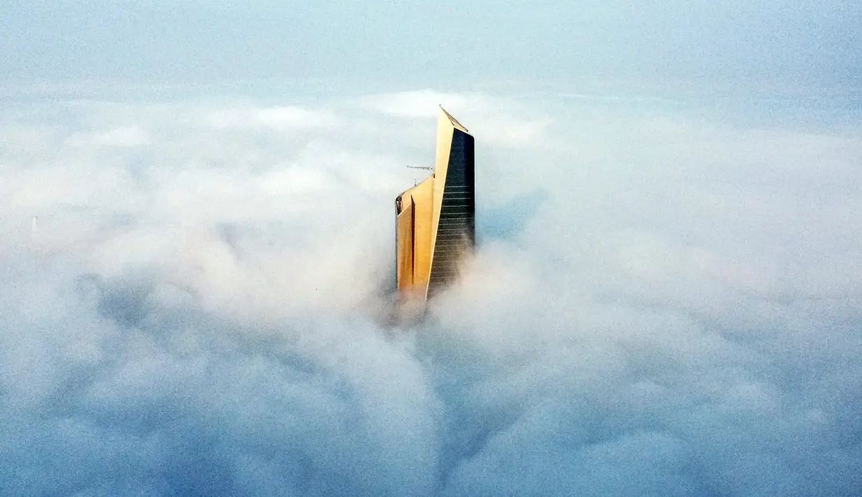 Pemandangan udara memperlihatkan puncak Al Hamra Tower di antara kabut tebal, Kuwait City, 23 Januari 2023. Al Hamra Tower digunakan sebagai kantor dan sekitar empat lantai untuk mal. (YASSER AL-ZAYYAT/AFP)