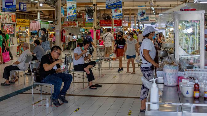 Orang-orang menjaga jarak sosial saat duduk menikmati makanan di sebuah pasar di Bangkok, Minggu (3/5/2020). Thailand mulai melonggarkan aturan pembatasan pergerakan orang dan pertemuan setelah diberlakukan beberapa minggu lalu dalam upaya memerangi penyebaran COVID-19. (AP/Gemunu Amarasinghe)
