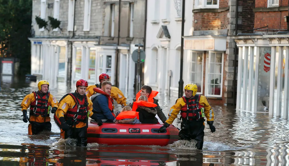 Petugas mengevakuasi warga yang terjebak banjir dirumahnya di Tadcaster, Inggris utara, Minggu (27/12). Banjir akibat luapan sungai Ouse yang telah memperburuk sejumlah wilayah Inggris utara. (REUTERS/Andrew Yates)