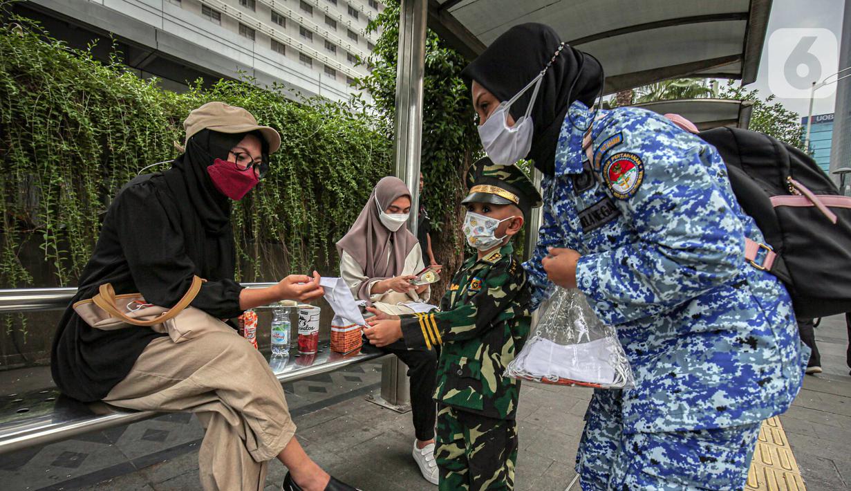 Perserta yang tergabung dalam Forum Kader Bela Negara DKI Jakarta membagikan bunga dan masker kepada warga di Jalan Thamrin, Jakarta, Rabu (22/12/2021). Aksi tersebut merupakan bentuk apresiasi terhadap kaum perempuan terutama pada peringatan Hari Ibu. (Liputan6.com/Faizal Fanani)