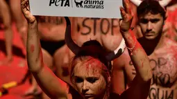 Seorang Aktivis berunjuk rasa memprotes adu banteng dalam Festival San Fermin di depan Balai Kota di Pamplona, Spanyol utara, (5/7). Festival ini melibatkan banyak orang dalam pertunjukan adu banteng, musik dan tarian. (AP Photo/Alvaro Barrientos)