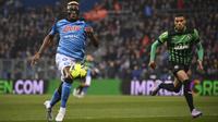 Pemain Napoli, Victor Osimhen (kiri) mengontrol bola dibayangi pemain Sassuolo dalam pertandingan pekan ke-23 Liga Italia 2022/2023 yang berlangsung di Mapei Stadium, Sabtu (18/2/2023). Victor Osimhen kini telah mencetak 18 gol dan menjadi top skor sementara Liga Italia musim ini. (AP/LaPresse/Massimo Paolone)