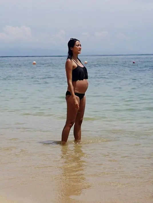 Pemeran dalam film Karma itu juga bersantai menikmati pantai. Tampil dengan bikini dan membiarkan perut buncitnya yang terus membesar terkena pasir atau sinar matahari. (Instagram/dominiquediyose)