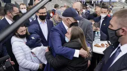 Presiden Amerika Serikat Joe Biden memeluk seorang gadis saat bertemu dengan pengungsi Ukraina dan pekerja bantuan kemanusiaan pada kunjungan ke PGE Narodowy Stadium di Warsawa, Polandia, 26 Maret 2022. (AP Photo/Evan Vucci)