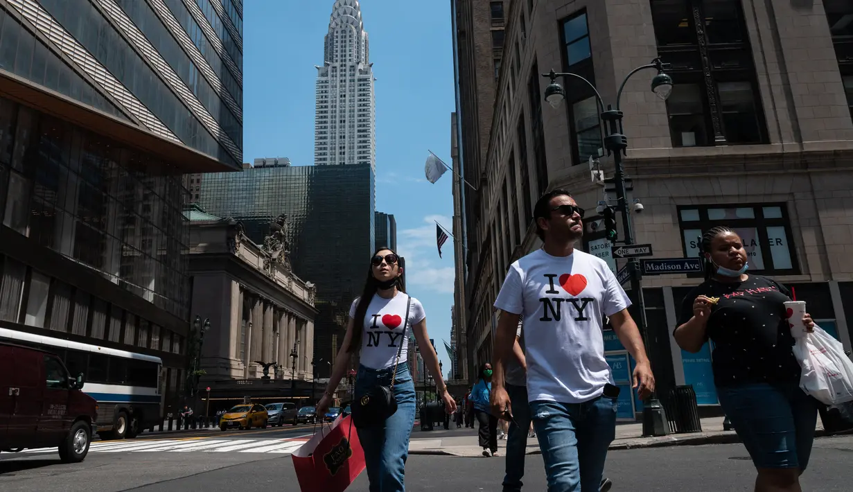 Orang-orang berjalan melewati Gedung Chrysler pada hari yang hangat di New York City (7/6/2021). Cuaca yang hangat di New York dimanfaatkan warga untuk membaca buku hingga berjalan-jalan. (AFP/Angela Weiss)