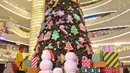Pengunjung melintas di dekat pohon Natal di Senayan City, Jakarta, Senin (21/12/2020). Pohon Natal ini didominasi permainan warna hijau, merah, putih dan emas dan sekeliling pohon Natal dengan beragam wrapping gift boxes warna-warni berukuran besar. (Liputan6.com/Herman Zakharia)