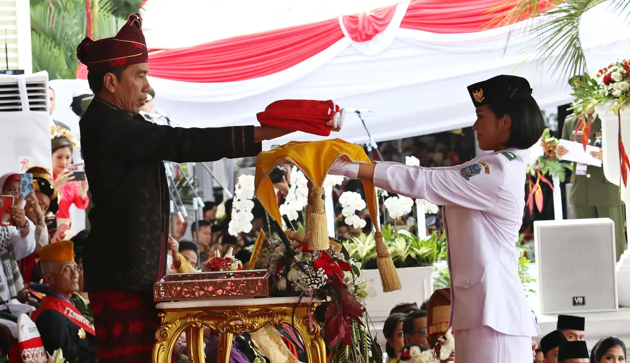 Presiden Jokowi menyerahkan Bendera Merah Putih kepada Fariza Putri Salsabila, anggota Pasukan Pengibar Bendera Pusaka (Paskibraka), saat Upacara Peringatan Detik-detik Proklamasi 17 Agustus di Istana, Jakarta, Kamis (17/8). (Liputan6.com/Pool)