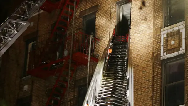 Pemadam kebakaran saat melakukan evakuasi setelah kebakaran terjadi sebuah apartemen lima lantai di Bronx, New York