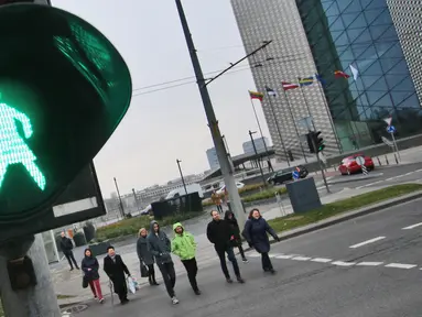 Orang-orang menyeberang jalan dengan lampu lalu lintas bergambar wanita di Vilnius, Lituania, Jumat (2/11). Hal itu untuk merayakan ulang tahun ke-100 wanita memperoleh pengakuan internasional dalam pemungutan suara di negara baltik. (Petras Malukas/AFP)
