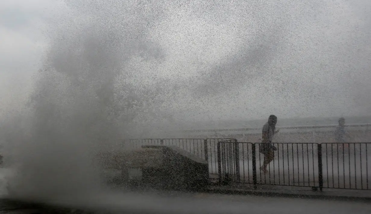 Warga berlari ketika ombak besar menghantam pesisir Hong Kong menyusul terjangan Topan Haima, Tiongkok, Jumat (21/10). Sebelum tiba di Hongkong, topan Haima terlebih dulu menerjang Filipina. (REUTERS/Bobby Yip) 