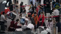 Orang-orang mengantre check-in untuk penerbangan domestik menjelang liburan "Golden Week" di Bandara Internasional Ibu Kota Beijing pada 30 September 2020. Gelombang liburan melanda China yang warganya merayakan libur panjang, yang dikenal dengan Golden Week. (NICOLAS ASFOURI / AFP)