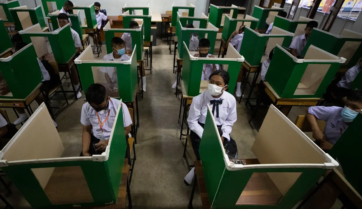 Para siswa dengan mengenakan masker duduk di mejanya yang menggunakan partisi di Samkhok School di Pathum Thani, Bangkok, Rabu (1/7/2020). Thailand memulai fase kelima relaksasi pembatasan covid-19 yang memungkinkan pembukaan kembali sekolah-sekolah setelah ditutup sejak Maret. (AP/Sakchai Lalit)